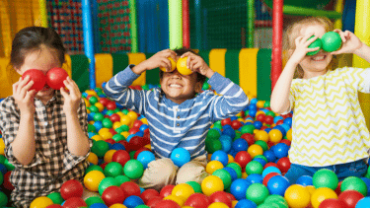 three happy kids playing in ball pool